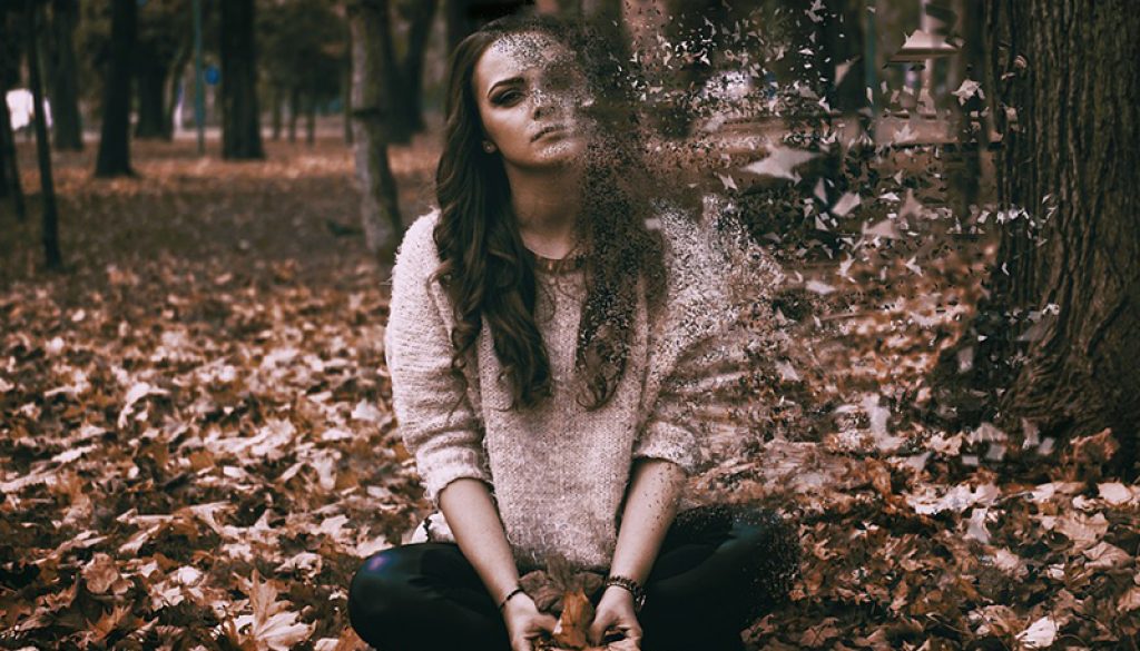 photo of young woman sitting in fall leaves with half of her face and body is disintegrating Colorado TMS